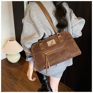 Détail du sac cabas marron en suédine avec plaque logo en métal et poche zippée à franges