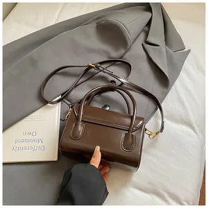 Detail of vintage dark brown glossy leather handbag with gold metal hardware and strap