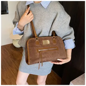 Détail du sac cabas rétro marron montrant la texture en daim et logo en métal