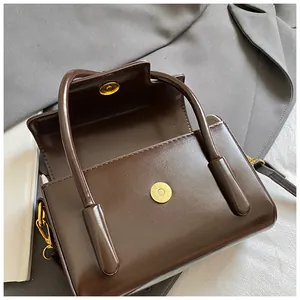 Close-up of dark brown glossy leather handbag with gold magnetic clasp and buckle details