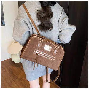 Gros plan d'un sac cabas en cuir mat marron avec zips à franges et longues anses