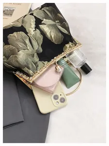 Détail d'une pochette brodée montrant le rangement pour maquillage et téléphone