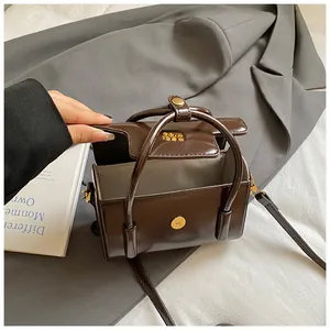 Detail of vintage coffee brown square bag showing glossy leather and golden magnetic buckle