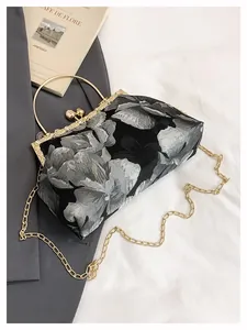 Détail de broderie florale sur sac bandoulière avec poignée dorée et fermoir en cristal