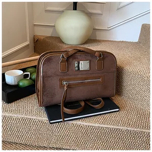 Détail du sac cabas en daim marron avec plaque métallique et poche zippée à l'avant