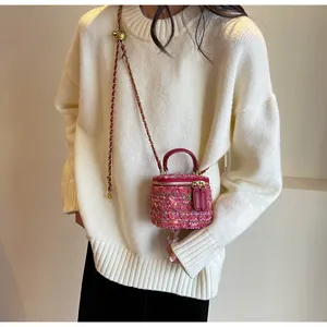 Detail of pink tweed mini bag showing red leather handle and gold chain strap