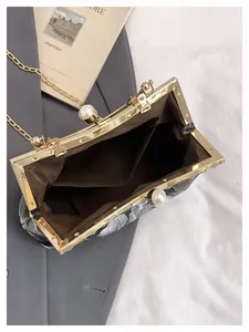Détail de pochette de soirée brodée vintage avec fermoir perle et bandoulière chaîne
