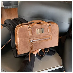 Détail du sac cabas caramel avec textures en daim, plaque argentée et accents de glands
