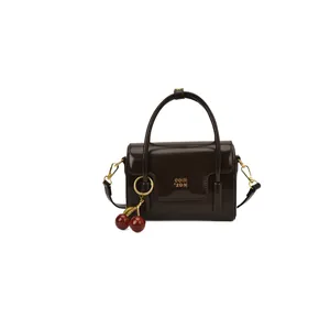 Vintage coffee brown glossy leather handbag with golden logo and cherry charm accessory