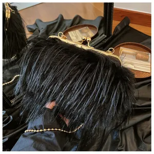 Detail of black feather evening bag with golden kiss-lock closure and metal chain