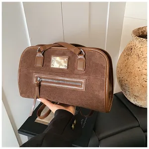 Détails d'un cabas en daim marron foncé avec bordure en cuir et tirette de zip décorative