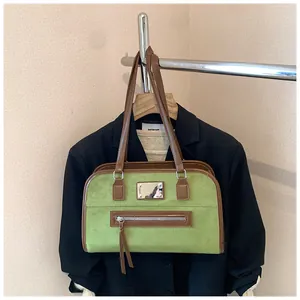 Détail du cabas en daim vert avec garniture en cuir marron sur une veste