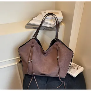 Detail of vintage brown tote bag with woven cords and metallic hardware on soft suede texture