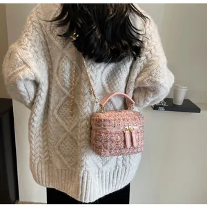 Rosa Tweed Umhängetasche mit Kette am Model, kombiniert mit einem beigen Pullover