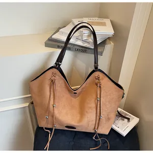 Detail of camel brown suede tote bag with decorative drawstrings and silver beads