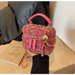 Detail der rosa Tweed-Eimertasche mit goldener Kette und rundem Metallverschluss
