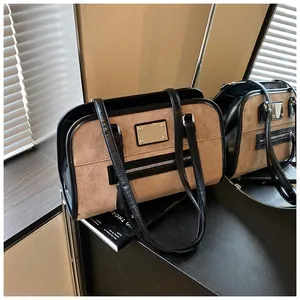 Détail des coutures en daim marron et cuir noir sur un sac à main rétro Boston chic