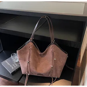 Close-up of vintage brown suede tote bag featuring fringe details and silver hardware