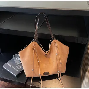 Detail of caramel suede tote bag featuring side drawstrings and silver metal beads