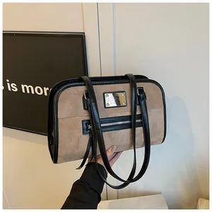 Gros plan du sac cabas rétro en daim camel avec garniture en cuir noir et logo métal