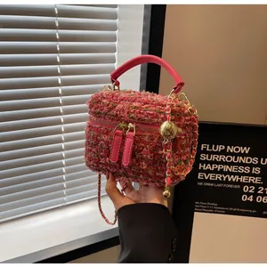 Detail der Tweed-Textur und goldener Kugelkette an einer rosa Luxus-Schminktasche