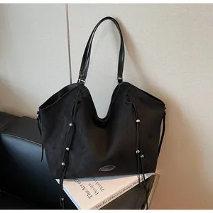 Macro shot of large black suede tote bag with drawstring details and silver metal beads