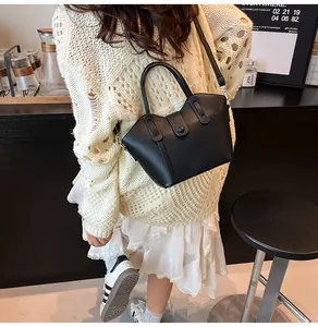 Détail d'un sac seau en cuir grainé noir avec poignée supérieure et fermeture à boucle pression