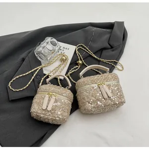 Détail de sacs seaux en tweed à paillettes avec anses cuir et bandoulières dorées