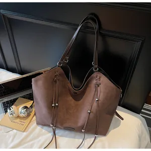 Detail of soft dark brown suede tote bag with drawstring tassels and spacious interior