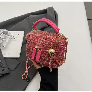 Détail du mini sac en tweed rose avec chaîne à boule dorée et poignée en cuir chic