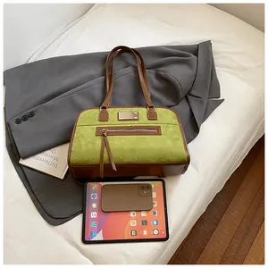 Détail du sac rétro en daim vert avec garniture en cuir marron et fermeture éclair à glands
