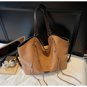 Detail of tan suede tote bag featuring fringe drawstring and silver metal bead accents