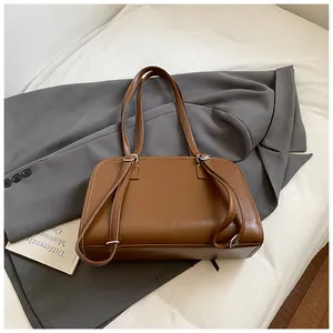 Détail du sac fourre-tout en cuir caramel sur une veste grise, style vintage