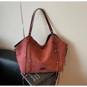 Detail of burgundy suede tote bag featuring fringe tassels and high-quality leather texture