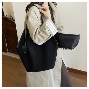 Ensemble cabas noir minimaliste avec pochette porté sur un trench-coat beige élégant
