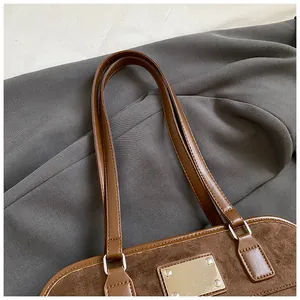 Détail du sac cabas en cuir marron et daim avec une plaque métallique décorative