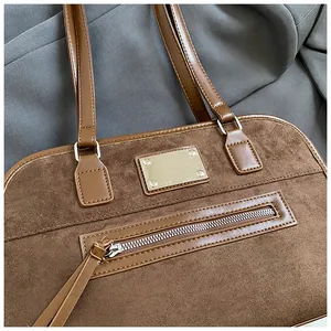 Détail d'un sac cabas marron en daim avec finitions argentées et pompon rétro
