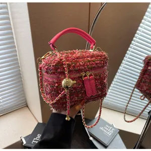 Detail der rosa Tweed-Umhängetasche mit Goldkette und dekorativem goldener Kugelanhänger