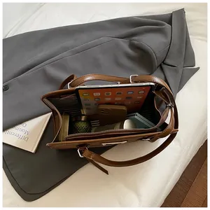 Vue de dessus de l'intérieur du cabas en cuir marron avec doublure et objets du quotidien
