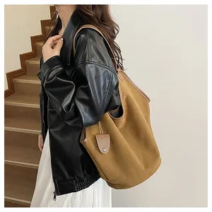 Détail d'un grand sac cabas marron en toile avec bordures en cuir et pendentif décoratif