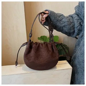 Detail einer dunkelbraunen Wildleder-Schultertasche mit Kordelzug und dezenter Prägung