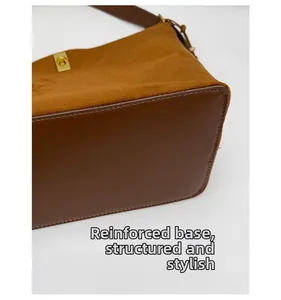 Detail of brown suede bucket bag with reinforced base and golden metallic hardware lock