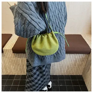 Olivgrüne Plissee-Umhängetasche kombiniert mit grauem Zopfstrickpullover für den Herbst