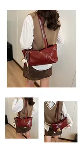 Detail of dark red patent leather shoulder bag with creative baseball charm and straps