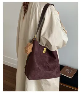 Detail of dark purple suede tote bag with golden lock and plush star pendant charm