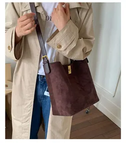 Detail of dark brown suede bucket bag with gold twist lock and long leather shoulder strap