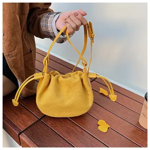 Detailansicht der gelben Wildleder-Beuteltasche mit Kordelzug und geprägtem Logo-Design