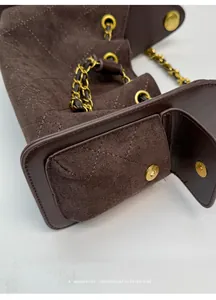 Macro detail of retro quilted suede bag with gold magnetic snap and chain link strap