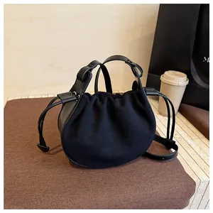Detail einer schwarzen Wildleder-Beuteltasche mit Kordelzug auf gemütlichem Café-Hintergrund