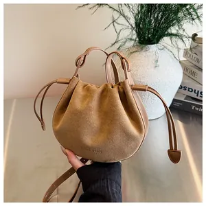Nahaufnahme der beigefarbenen Wildleder-Beuteltasche mit Logo-Prägung und Leder-Details
